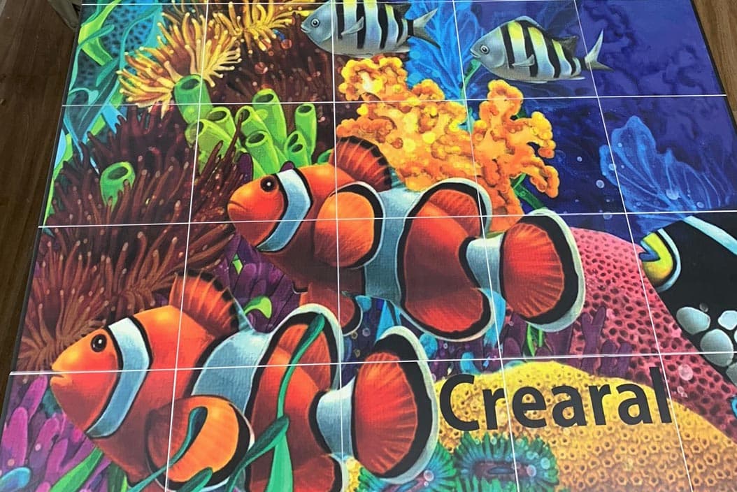 Mural de peces payaso y coral en azulejo, montado sobre la mesa del taller