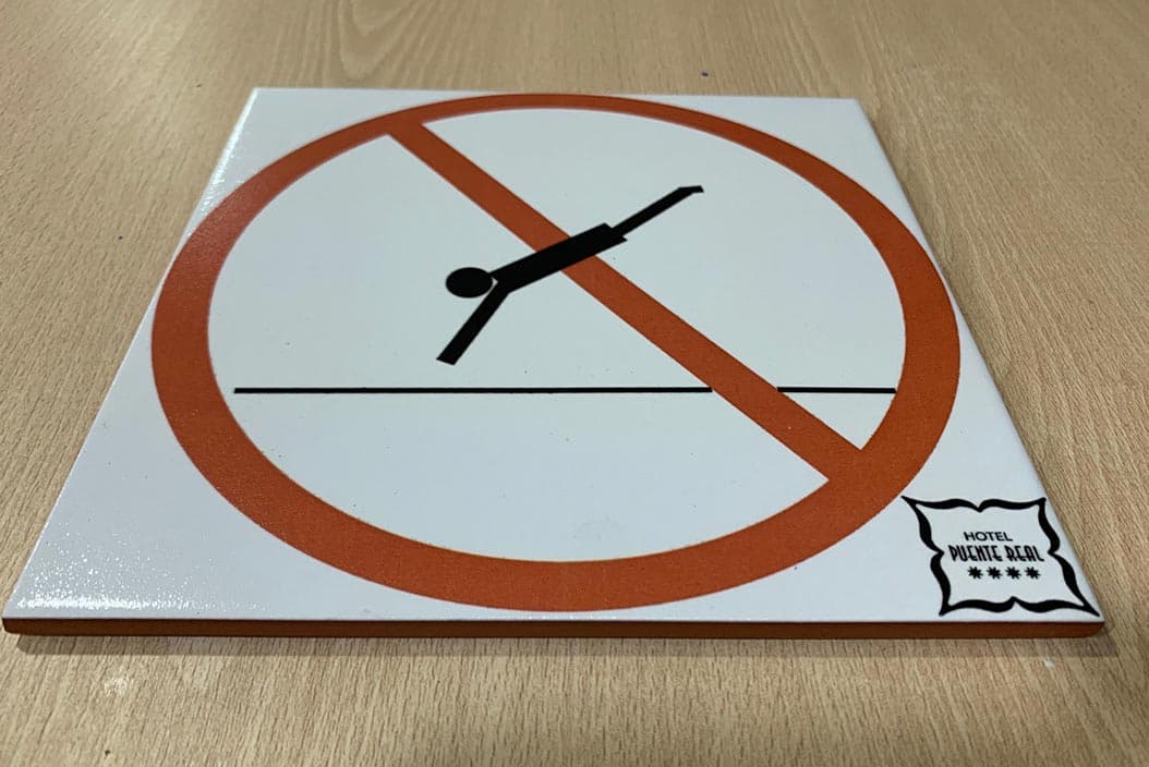 Azulejo personalizado con la señal de prohibido tirarse de cabeza y el logotipo de un hotel