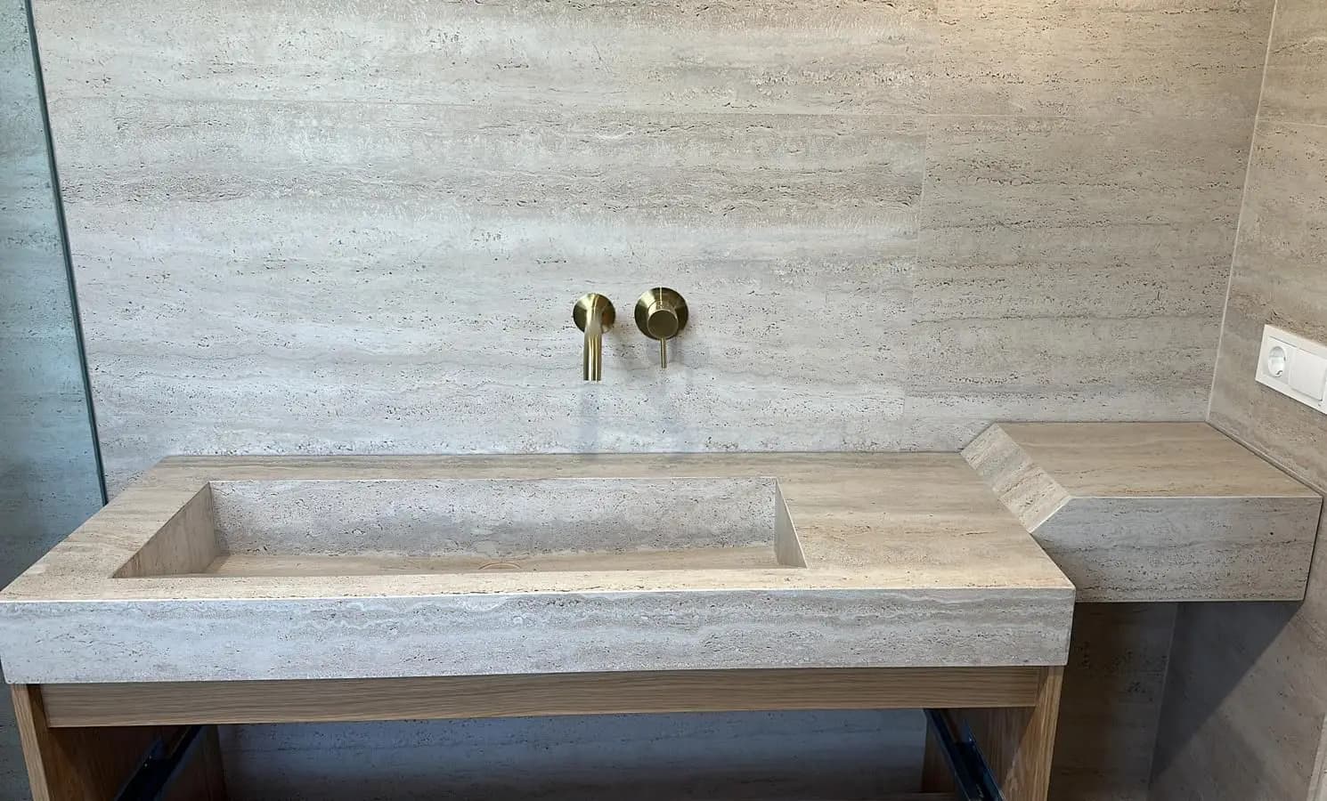 Encimera de lavabo con seno integrado y balda a inglete, del mismo porcelánico efecto travertino que la pared