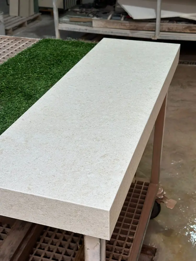Pieza gruesa de porcelánico claro con el canto unido a inglete, en el taller