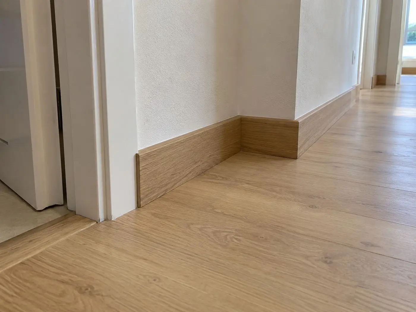 Rodapié de porcelánico efecto madera a juego con el suelo de un pasillo