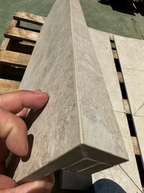 Pieza de porcelánico gris con la huella y la tabica unidas a inglete, en el taller