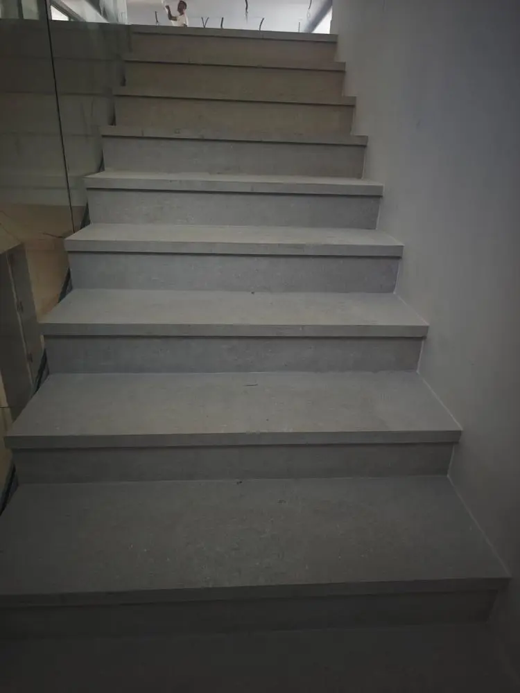 Escalera de obra con huella y tabica de porcelánico gris, recién colocada