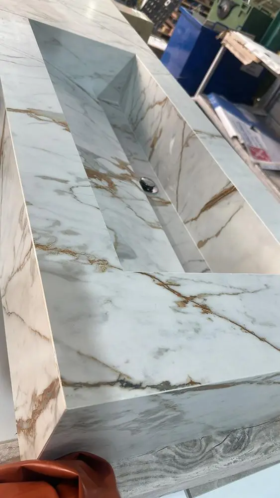 Lavabo de porcelánico efecto Calacatta montado a inglete en el taller, con el fondo en pendiente hacia el desagüe