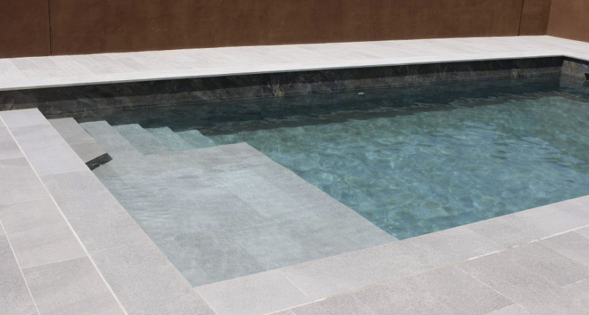 Piscina con coronación, playa y escalera en porcelánico gris claro