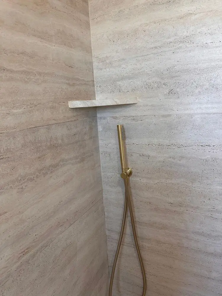 Balda de esquina en la ducha, cortada del mismo porcelánico efecto travertino que el alicatado
