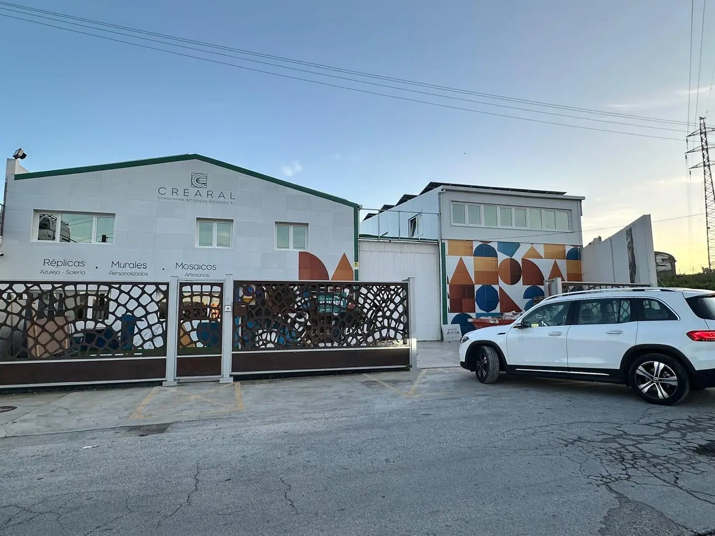 Fachada de la nave de Crearal con un mural geométrico de azulejos naranja, azul y blanco