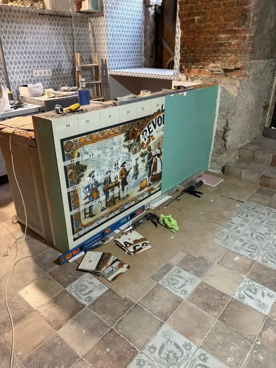 Mural costumbrista en azulejo revistiendo la barra de un local en obra