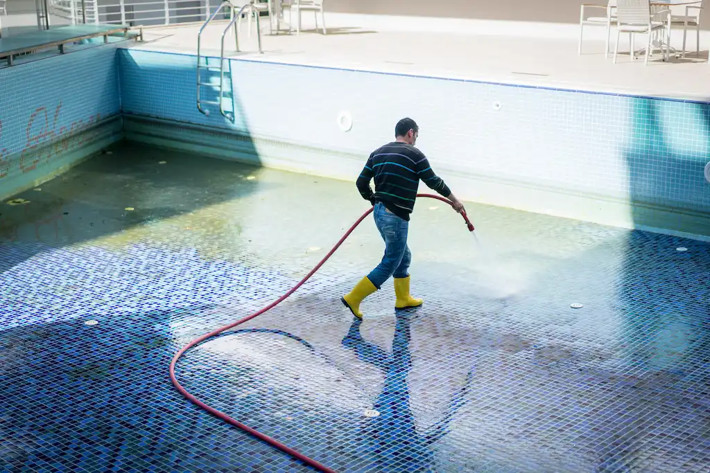 hombre limpiando la piscina de gresite